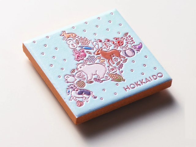 北海道の形をモチーフにした、動物や植物がカラフルに描かれた水色の四角いオブジェ