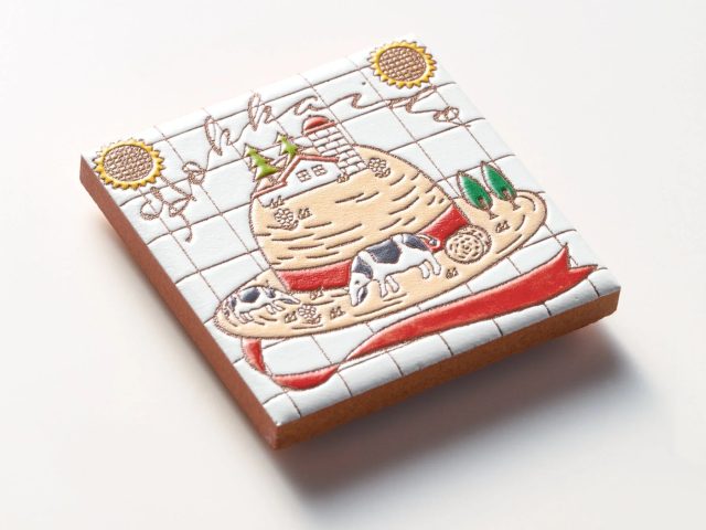 白いタイル風のクッキーに、牧場のような風景が描かれています